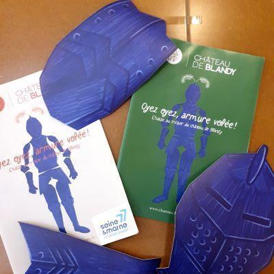 deux carnets avec une armure dessinée accompagnés de morceaux d'armure