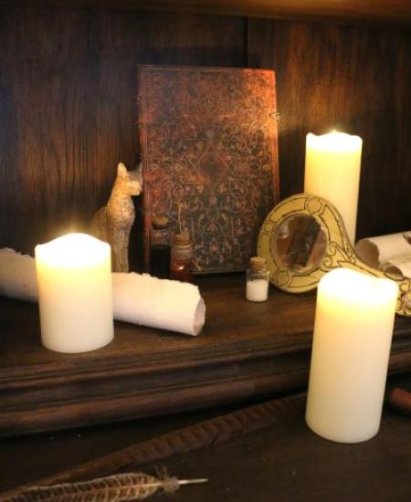 image représentant des bougies, un miroir, des fioles et une statuette de chat